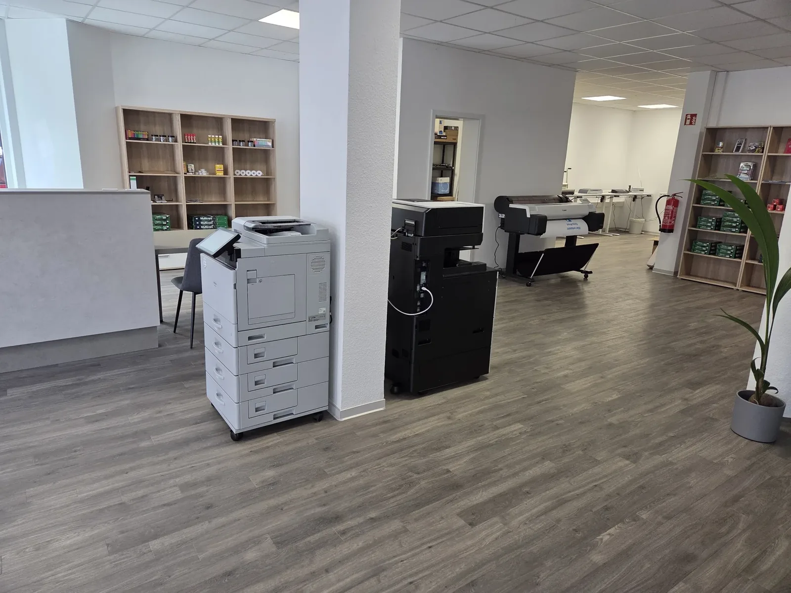 Zwei Multifunktionsgeräte und ein Großformatdrucker im Ladenlokal am Neutor, links Theke und Regale mit Papier